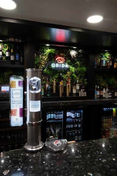 Bar counter with drinks display and illuminated signage in a stylish setting.